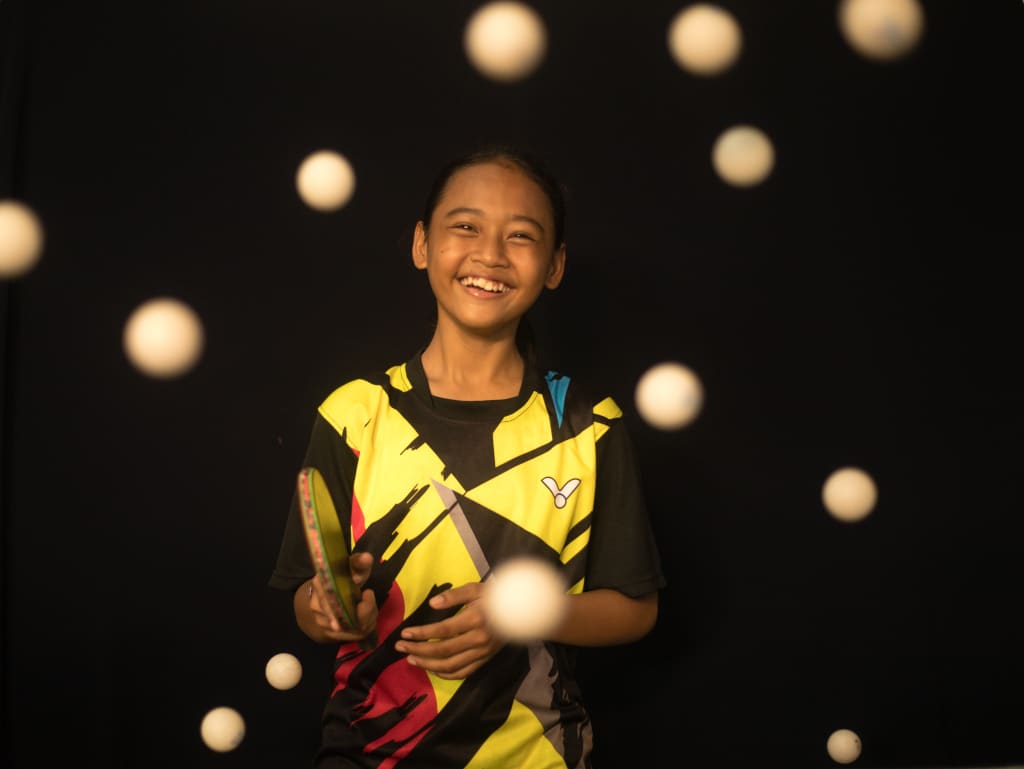 A young girl smiling while playing ping pong.
